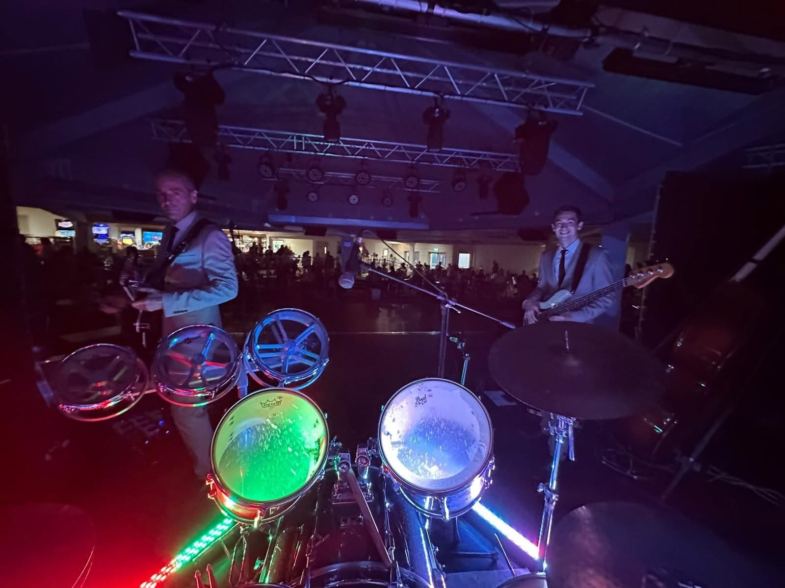 Full band on a big stage with teal drapes and dancers